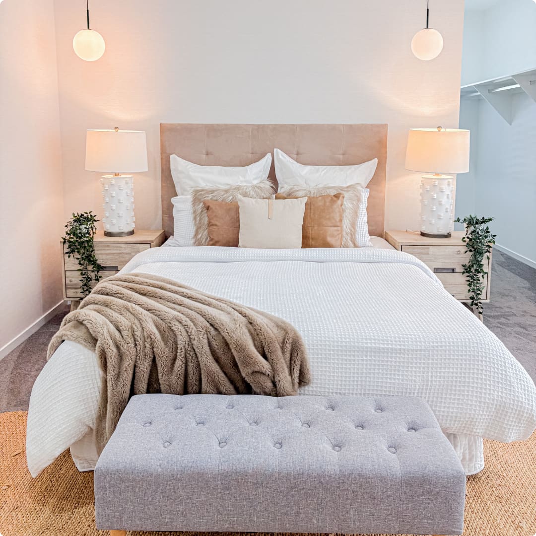 Large professionally styled bedroom with coordinated neutral furniture